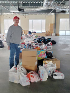 man stands next to a box and bags full of toys