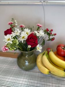 A small bouquet of red and white flowers sitting next to a bunch of bananas