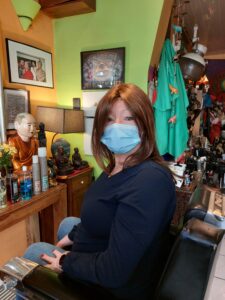 A woman looks at the camera wearing a brand new, brown wig and a blue face mask.