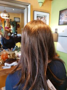 A woman looks at herself in the mirror wearing a brand new, brown wig.