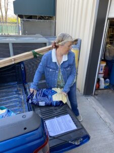 From the back of her truck, Monica unloads a large bag of dog food at the Pet Refuge