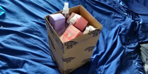 A cardboard box sits on blue fabric and is filled with smaller boxes of period products