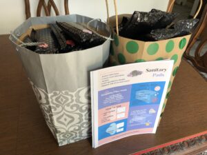 2 paper bags filled with period packs and instructions
