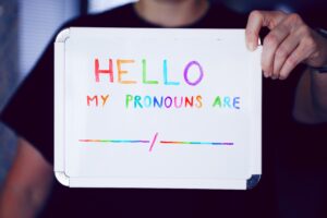 A white board with the words "Hello My Pronouns Are [blank space] / [blank space]" in rainbow color
