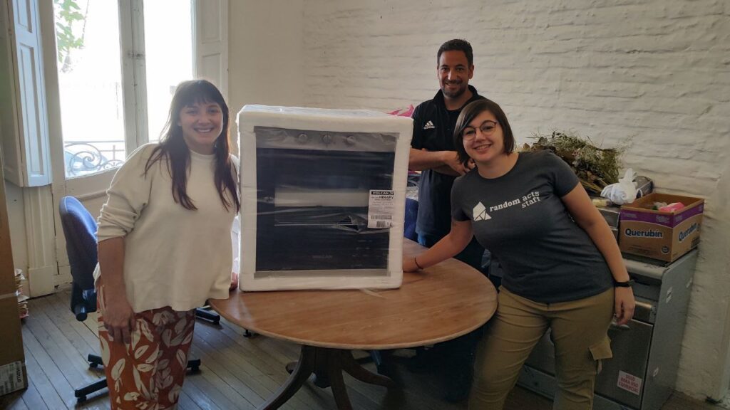 Three smiling people stand around a brand new oven.